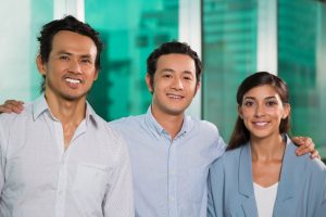 Three smiling, friendly Filipino business people embracing.