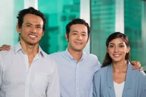 Three smiling, friendly Filipino business people embracing.
