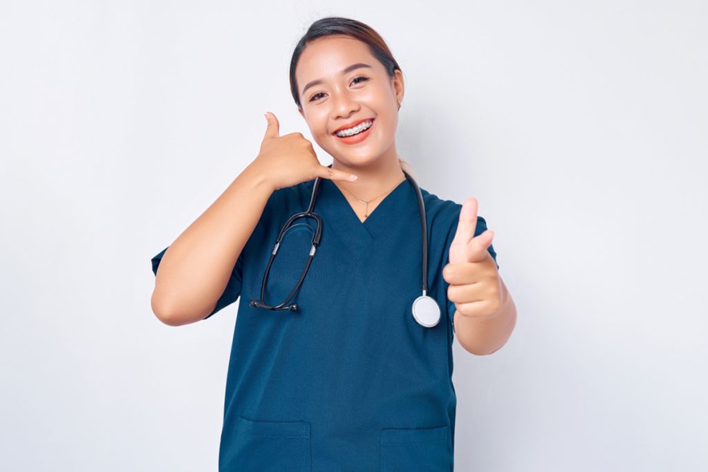 A female nurse, dressed in a blue uniform, is making phone gestures. You can also look for "virtual medical scribe jobs near me" if you're interested in similar positions.
