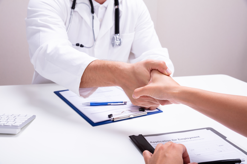 Doctor shaking hands with a female nurse in a clinic offering Virtual Medical Scribe Jobs Near Me.