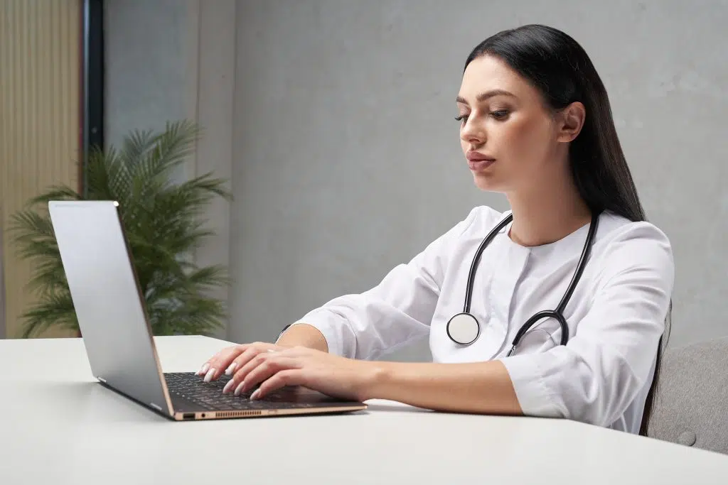 female doctor using her laptop, medical scribe virtual assistant