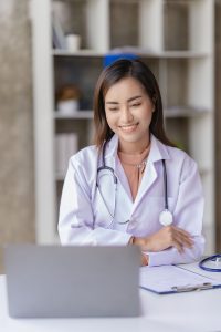 a doctor smiling while looking at her laptop