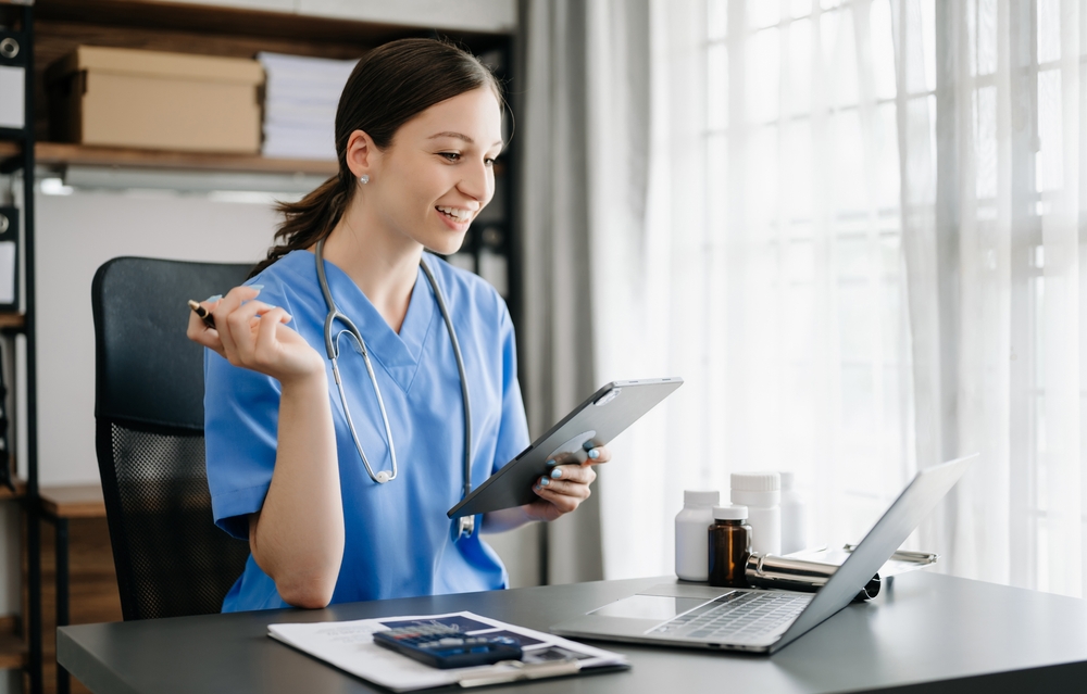 A part time work from home virtual medical scribe working on her ipad and laptop at home.