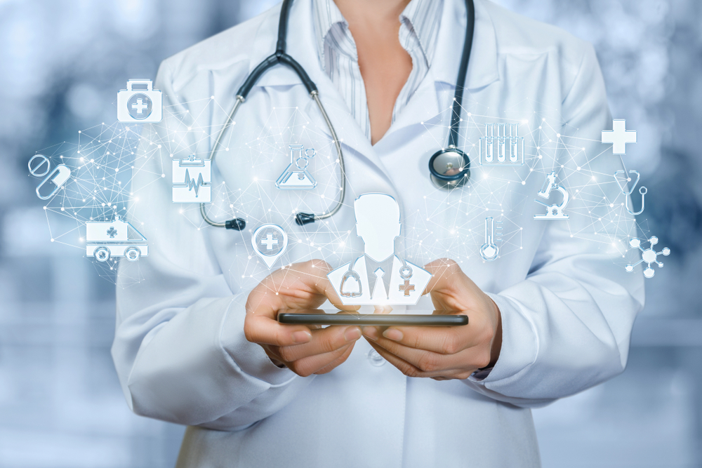 An innovative medical receptionist is holding a phone displaying a male doctor on the screen.