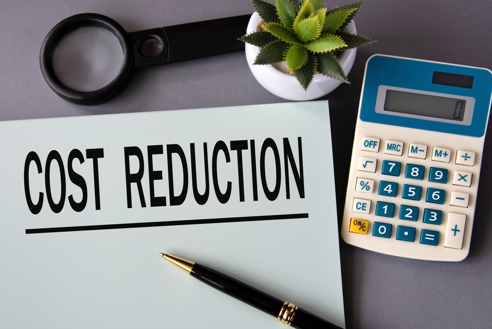 COST REDUCTION - words on paper with a pen on the background of a calculator.