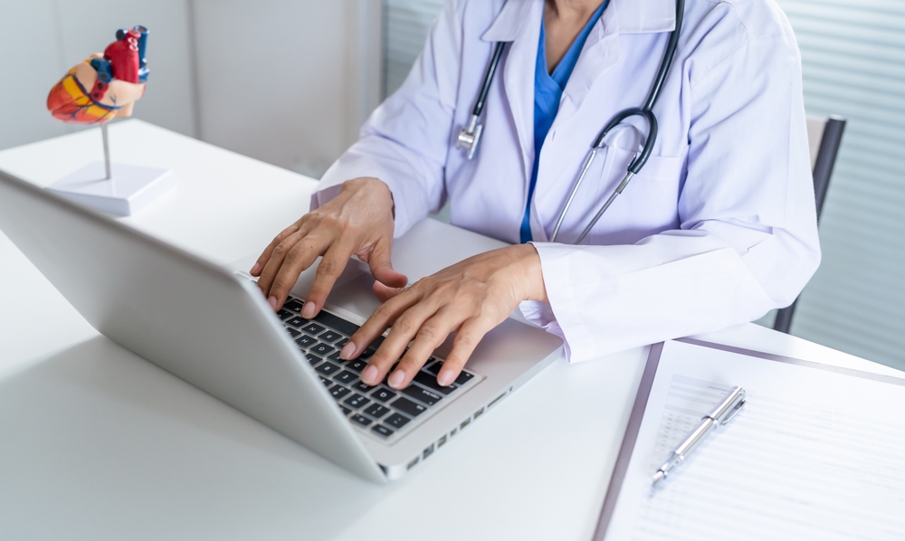 Cardiologist medical virtual scribe, documenting on her laptop.