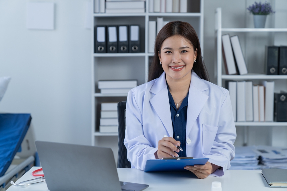 Female cardiologist medical scribe sitting at her desk in an office.