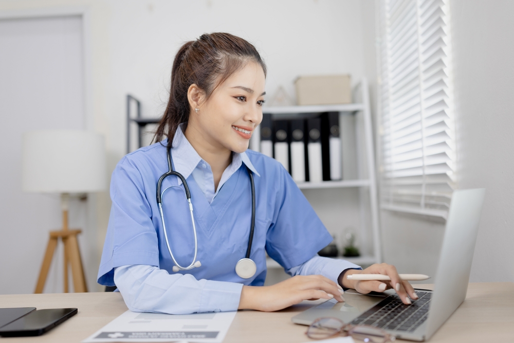 Female medical scribe happily working on her laptop