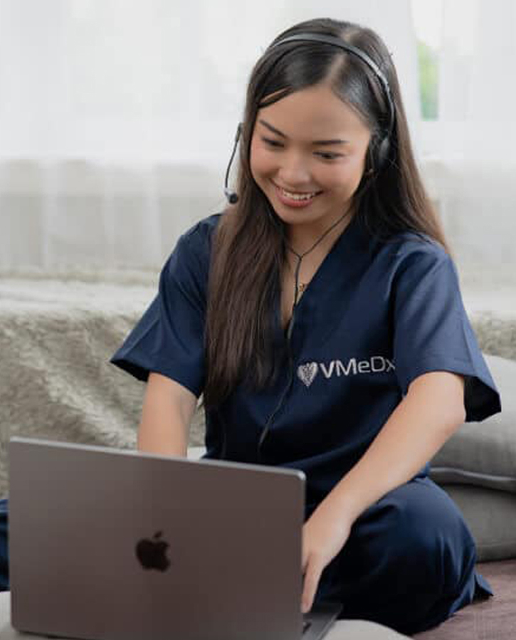 VMeDx-medical-administrative- assistant-working-wearing-headset-working-on-her-laptop
