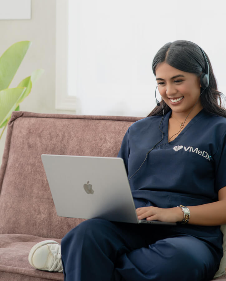 VMeDx virtual medical receptionist, VA working on her laptop while wearing headset.