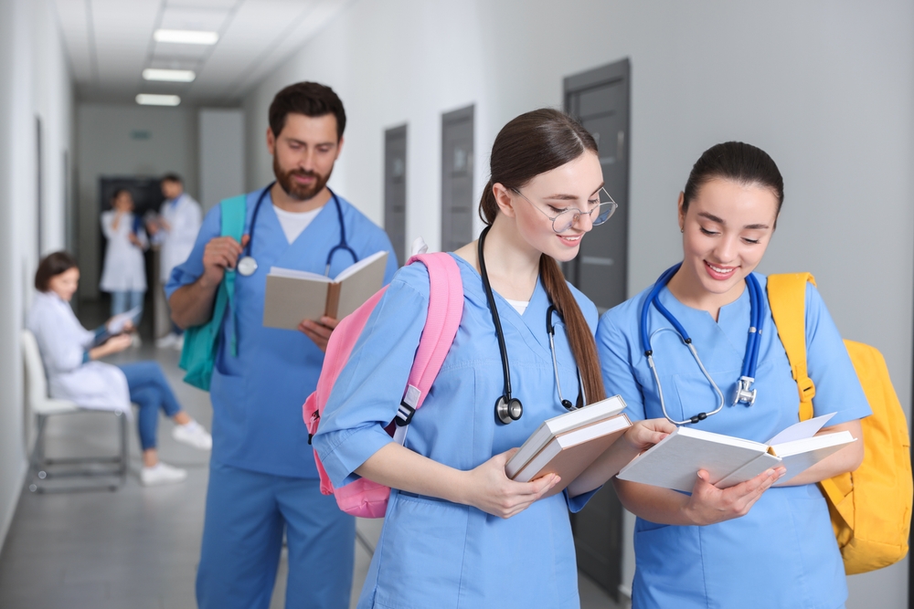 medical students with books in college hallway.