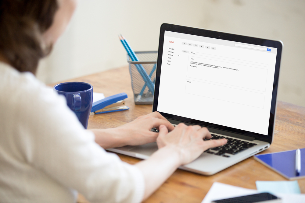 Female medical scribe in office types reply to letter email.