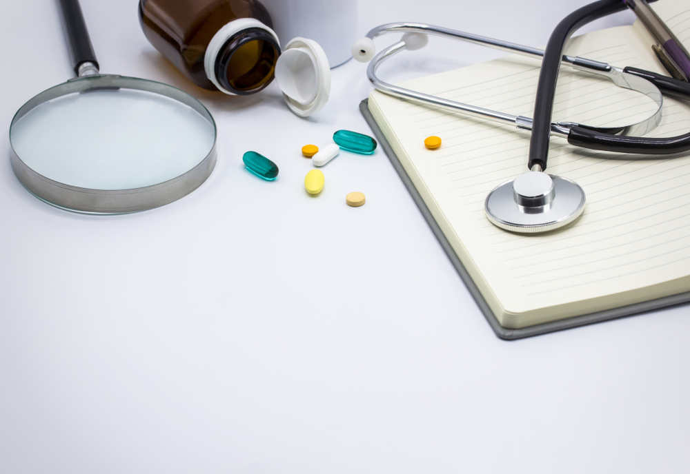Medical headphones with medicine and notebook isolated and magnifying glass.