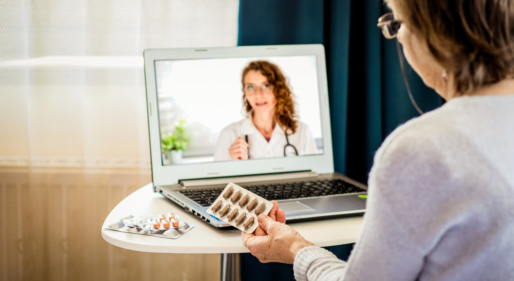 Telemedicine concept elderly woman using laptop and taking her blood pressure.