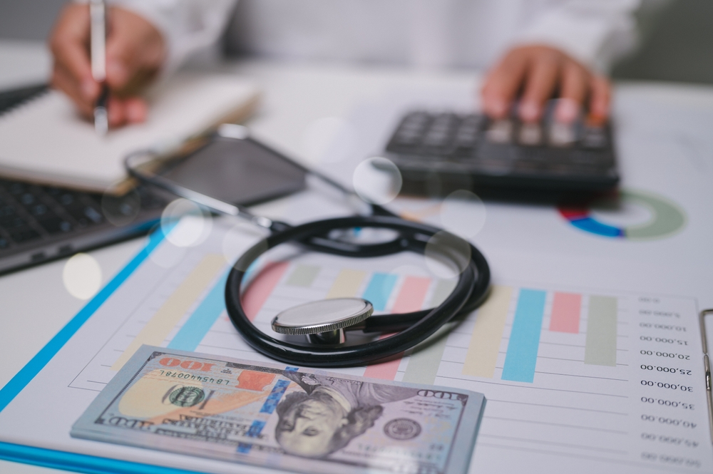This image showcases the intersection of healthcare and finance, featuring a stethoscope, dollar bills, and analytical tools, emphasizing the importance of managing medical costs effectively