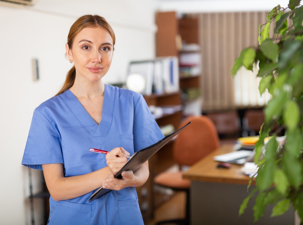 Virtual medical scribe in blue scrubs and with clipboard in hands.