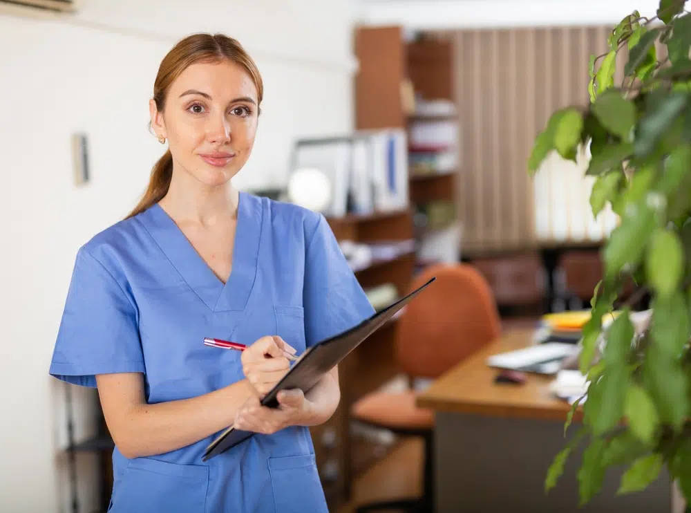 Virtual medical scribe in blue scrubs and with clipboard in hands.
