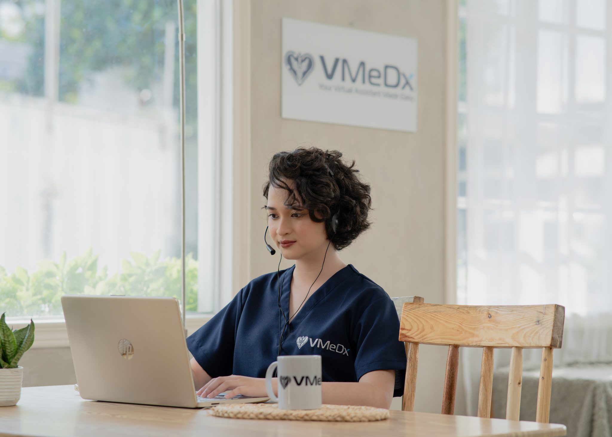 VMeDx virtual medical scribe documenting on her laptop