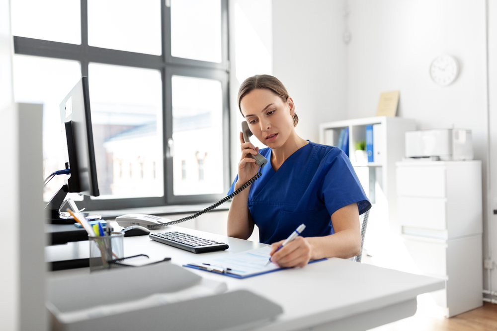 a receptionist talking to a phone with her client and scheduling an appointments.
