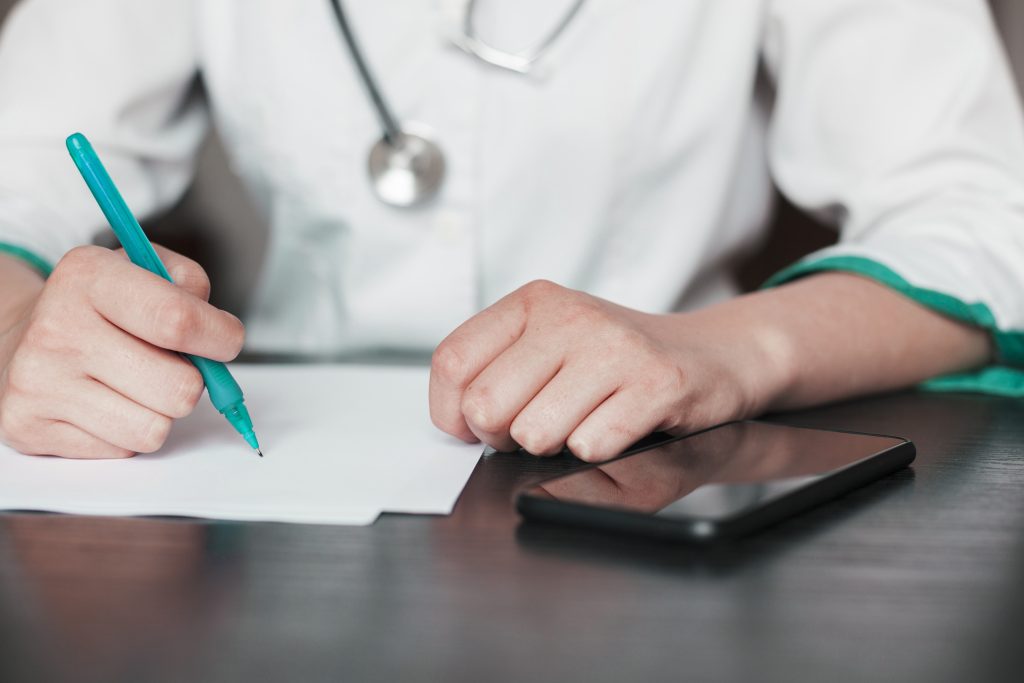 a cropped image of a doctor writing, certified medical scribe