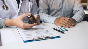 cropped hands of doctor explaining medicines, prior authorization for medication 
