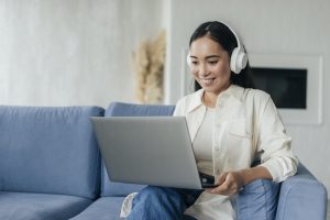 virtual assistant with headphones smiling staring at the laptop