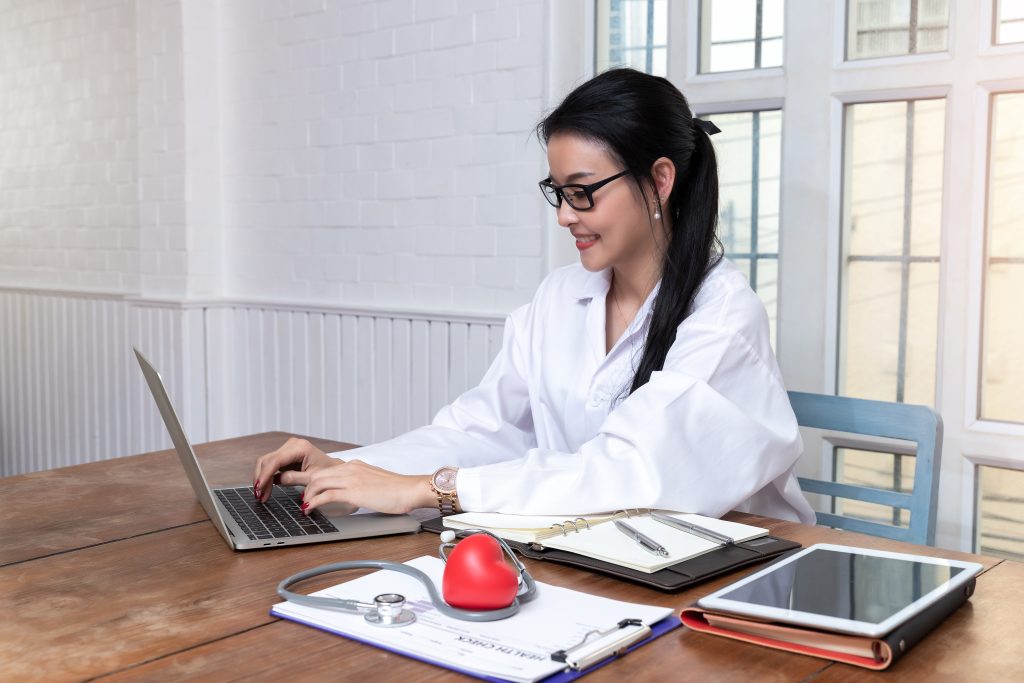 young female doctor sitting using her laptop, medical administrative assistant