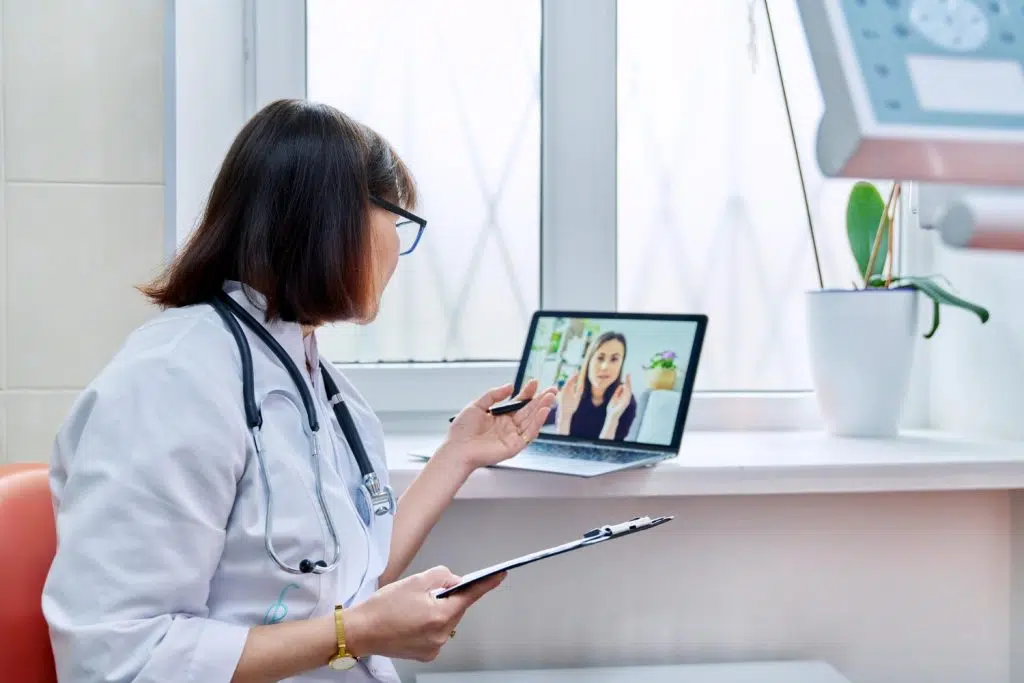 A doctor talks to her female patient on a video call with support from healthcare virtual assistants.