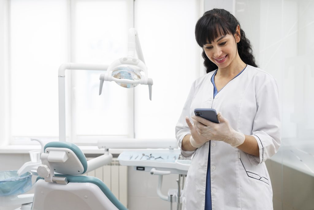 a dentist using her phone in the office, dental practice management