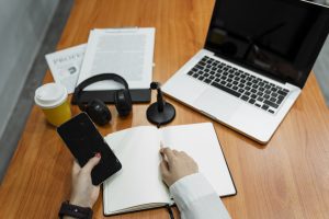 Cropped image of woman's hand with nail painting hold the smartphone at the wooden table.