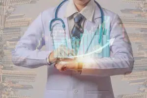 young doctor holding smart watch and touching visual screen of medical stock chart, dental office management