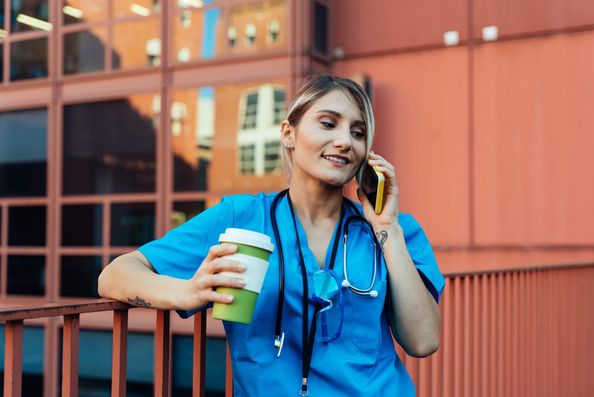 A virtual medical receptionist having coffee while talking on the phone.