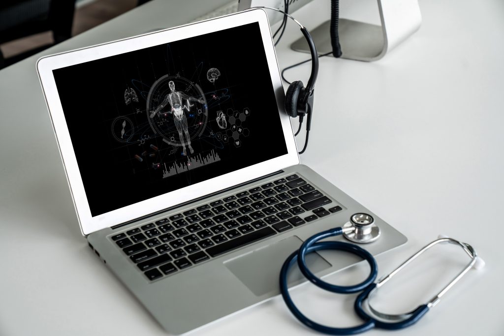 AI virtual receptionist setup with laptop, stethoscope, and headset on table.