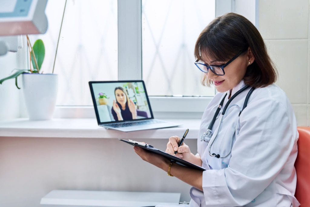 Dermatologist medical virtual scribe, talking on a video call with her patient.