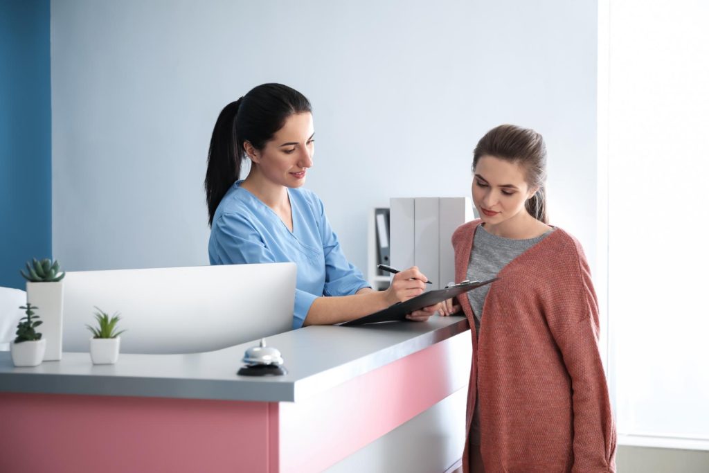 Patient loyalty receptionist assisting a patient at the hospital front desk.