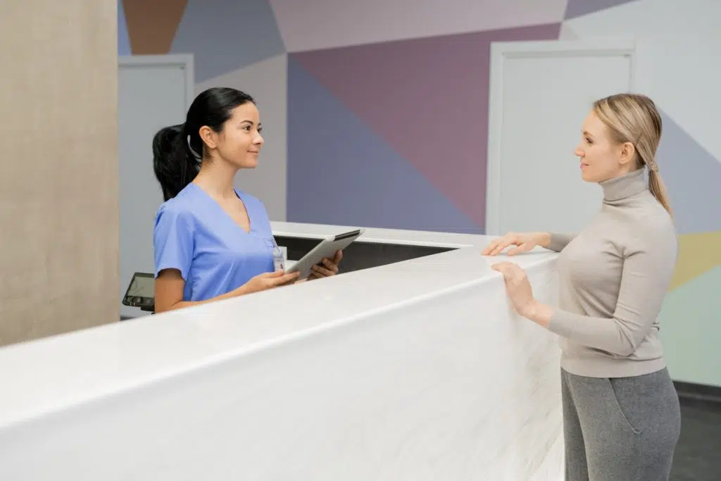 Remote medical reception services representative standing by the reception counter.