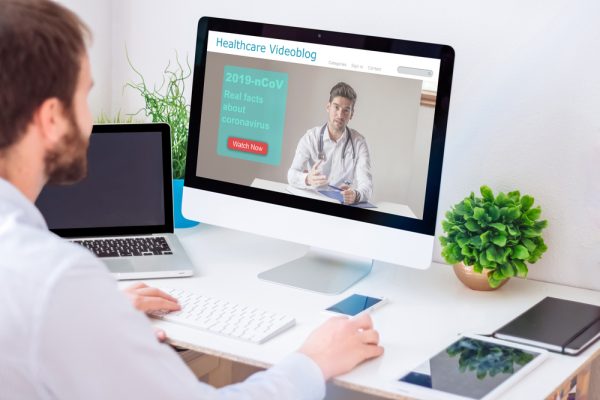 Young man using a computer to manage a healthcare video blog with medical SEO solutions.