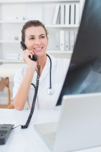 Doctor doing phone call while she using computer in medical office