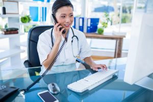 Doctor having phone call and using her computer in medical office, streamline efficiency receptionist