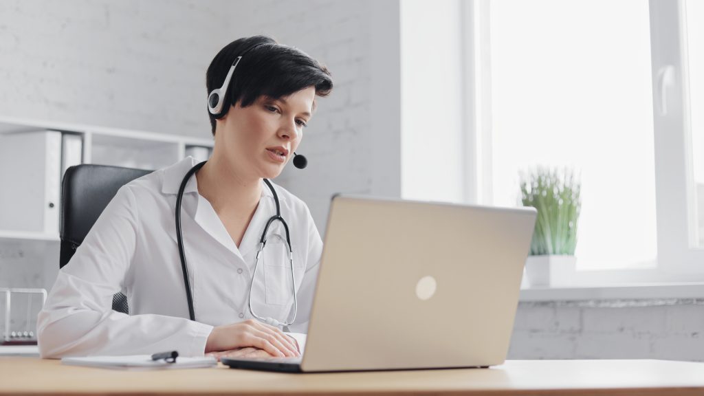 Female doctor consulting patient remote online using headset and web camera on laptop, remote clinic management support