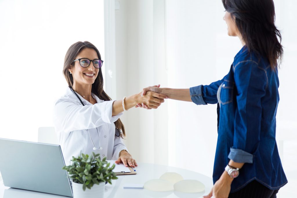 Portrait of female doctor and her patient shaking hands in the consultation. trustworthy receptionist