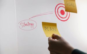 Goal, Plan, Challenge and Strategy Concept. Person making Business Plan on Sticky Note. Closeup and Selective Focus