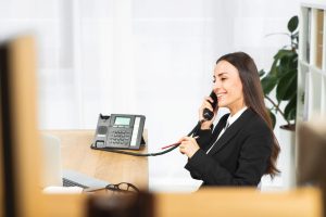 Successful young businesswoman talking on telephone with pencil in hand, black friday efficiency receptionist