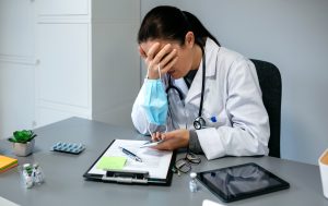 Unrecognizable worried female doctor with hands on face, healthcare challenges receptionist