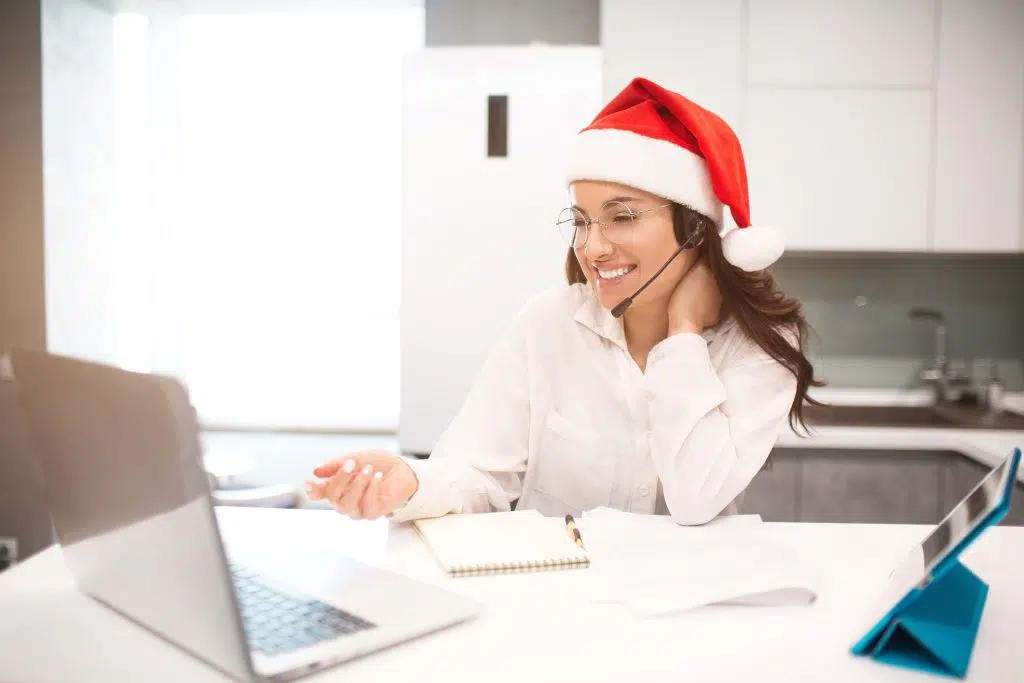 Woman in santa hat working on a laptop, winter preparation receptionist
