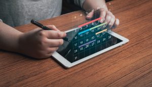 Woman use digital tablet to mark dates on virtual hologram calendar business schedule, international patient scheduling services