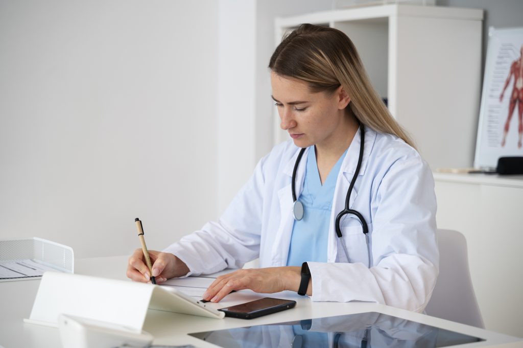 A medical scribe demonstrates what does a medical scribe do by writing notes at her desk.