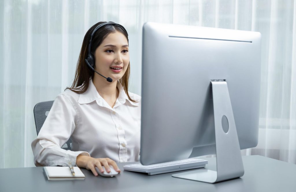 Female virtual receptionist jobs with headset works on laptop, focused and professional.
