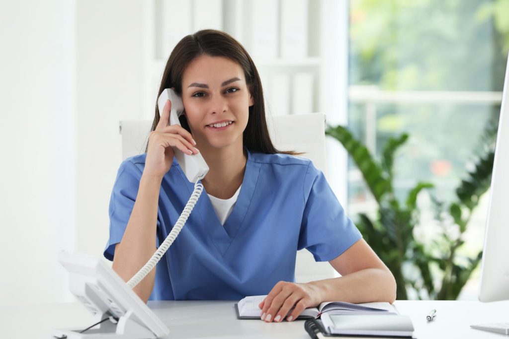 Medical receptionist on phone at desk showing 10 key job responsibilities of a Medical Receptionist
