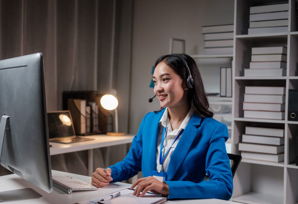 Woman wearing a headset working on a computer, providing virtual practice management support.